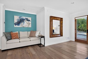 Quarto com sofá branco, parede de destaque em tons de verde-água e um espelho grande.