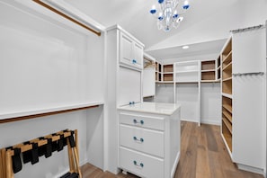 A walk-in closet with white cabinetry, wooden flooring, and a chandelier. - Pool + Hot Tub | Fire Pit + Hammock | Hilltop Valley Views | Vino Vista Villa (Paso Robles)