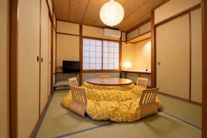 Una habitació tradicional japonesa amb fons de tatami, una taula rodona i portes corredisses.