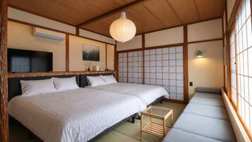 A traditional Japanese-style room with tatami flooring, a low wooden ceiling, and sliding shoji doors.