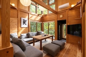 A modern interior with a wooden floor, a sofa set, a table, and a TV mounted on the wall. - KihadaNikko (Nikko)
