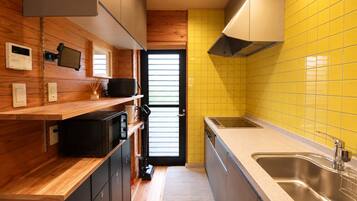 A compact kitchen with wooden cabinetry, a stainless steel sink, and a yellow tiled backsplash.