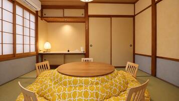 A traditional Japanese-style room with tatami flooring, a round wooden table, and shoji screens.