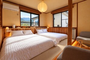 A room with two beds, a window with a view of mountains, a wooden ceiling, and a small table. - KihadaNikko (Nikko)