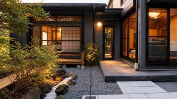 A modern building with a traditional Japanese interior, a well-maintained garden with rocks and plants, and a clear pathway leading to the entrance.