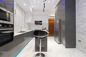 A modern kitchen with a built-in oven, a microwave, a sink, and a bar stool.