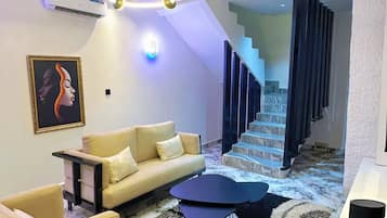 A modern living room with a sofa, coffee table, and a staircase leading to an upper floor.