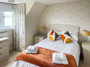 A neatly made bed with pillows, a bedside lamp, and a window with curtains. - 3 bedroom accommodation in Wemyss Bay (Wemyss Bay)