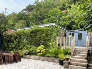 A garden with a wooden deck, a blue shed, and a staircase leading to a raised platform. - 3 bedroom accommodation in Wemyss Bay (Wemyss Bay)