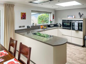A modern kitchen with a central island, built-in appliances, and a dining area with chairs. - 3 bedroom accommodation in Wemyss Bay (Wemyss Bay)