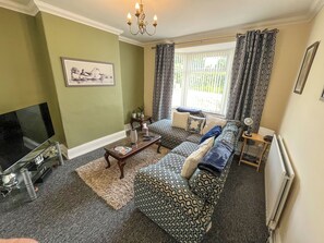 A living room with a sofa set, a television, a coffee table, and a window with curtains. - 2 bedroom accommodation in Fir Tree, near Bishop Auckland (Fir Tree, near Bishop Auckland)