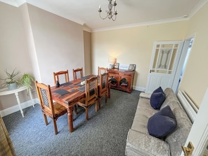 A dining area with a wooden table and chairs, a small side table with a lamp, and a door with decorative glass panels. - 2 bedroom accommodation in Fir Tree, near Bishop Auckland (Fir Tree, near Bishop Auckland)