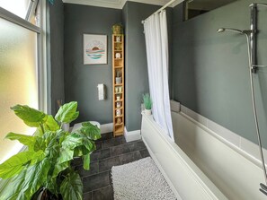 A bathroom with a shower, a white towel hanging, a plant, and a shelf with various items. - 2 bedroom accommodation in Fir Tree, near Bishop Auckland (Fir Tree, near Bishop Auckland)