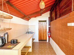 Una cocina con un lavamanos de acero inoxidable, una puerta de madera y un extintor.