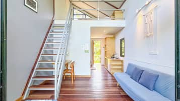 Una escalera que conduce a un nivel superior, un sofá azul y una pequeña zona de kitchenette.