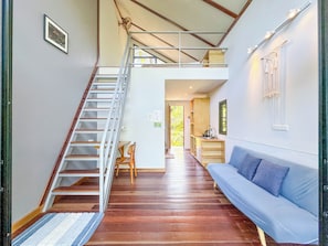 A staircase leading to an upper level, a blue sofa, and a small kitchenette area. - The Source (Ko Pha-ngan)