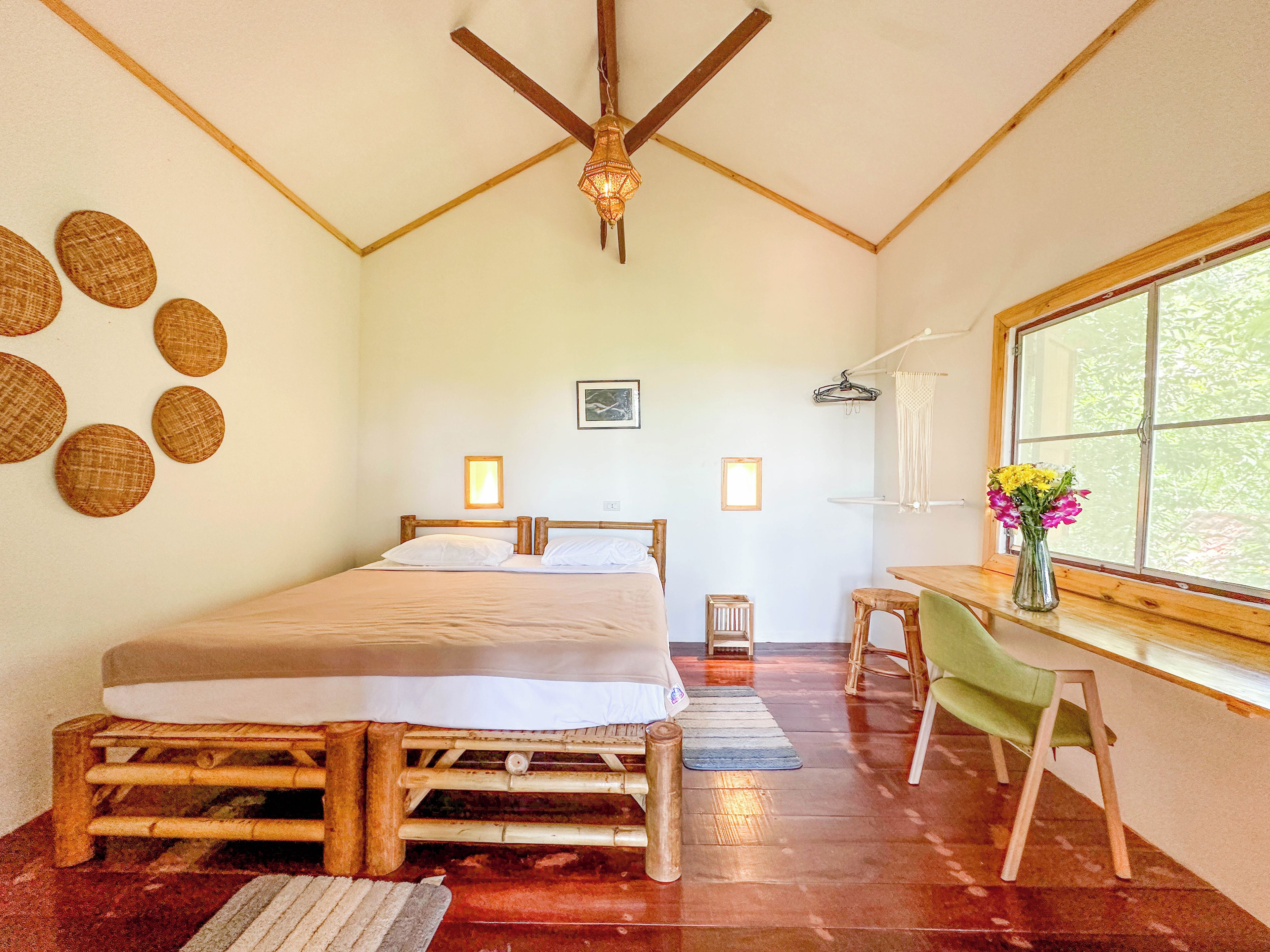 Ein Zimmer mit einem Bett, einem Schreibtisch, einem Stuhl, einem Fenster und einem Deckenventilator.