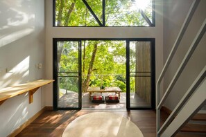 Habitación con un gran ventanal corredera que da a un espacio exterior, un banco de madera y un tapete redondo.