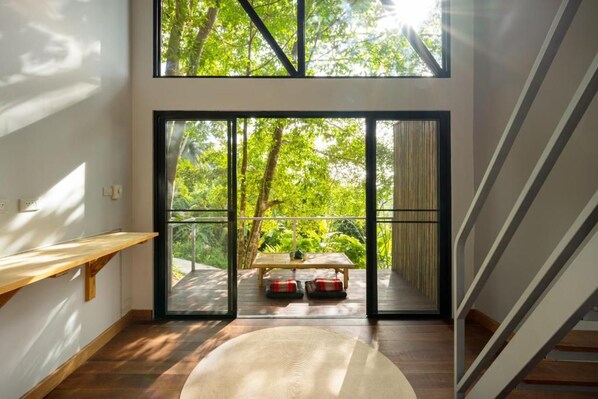 A room with a large sliding glass door leading to an outdoor area, a wooden bench, and a round rug.