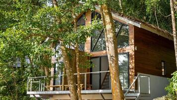 A modern treehouse with multiple levels, large windows, and a wooden exterior.