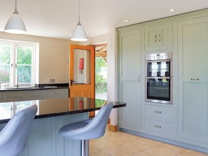 A kitchen with a central island, two bar stools, a double oven, and a view of greenery outside. - 4 bedroom accommodation in Coaley (Coaley)