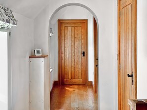 A hallway with a wooden door, white walls, and a white ceiling. - 4 bedroom accommodation in Coaley (Coaley)