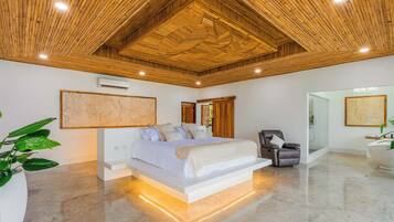 A modern bedroom with a large bed, a wooden ceiling, and a glass shower area.