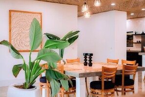 Una zona de menjador amb una taula de fusta, cadires, plantes en testos i il·luminació penjant.