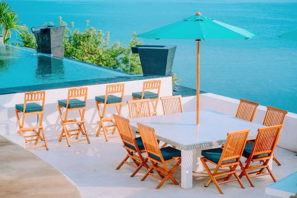 An outdoor dining area with a pool and ocean view.