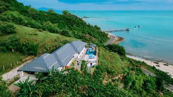 A coastal property with a swimming pool, a dock, and a view of the sea.