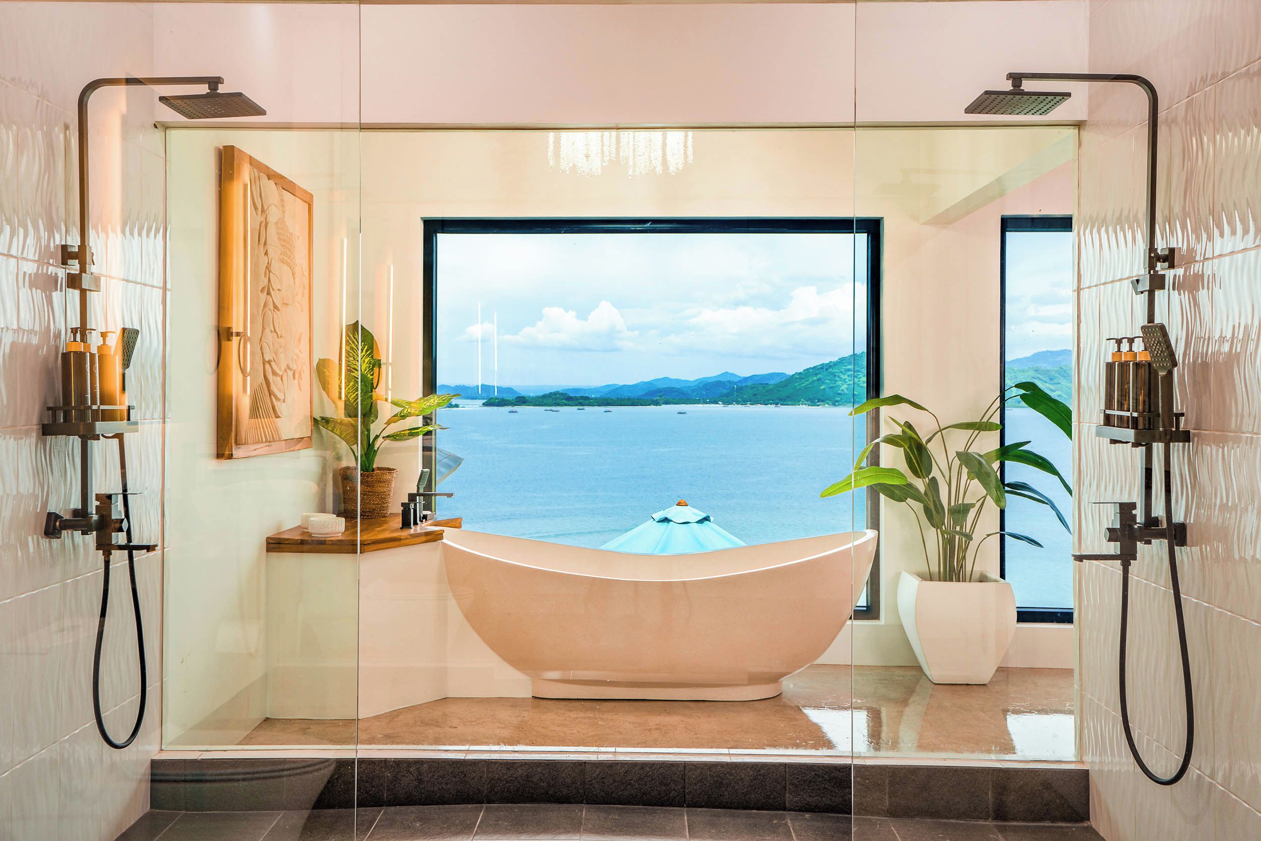 Un baño con una bañera grande, cabina de ducha de vidrio y vista a un cuerpo de agua.
