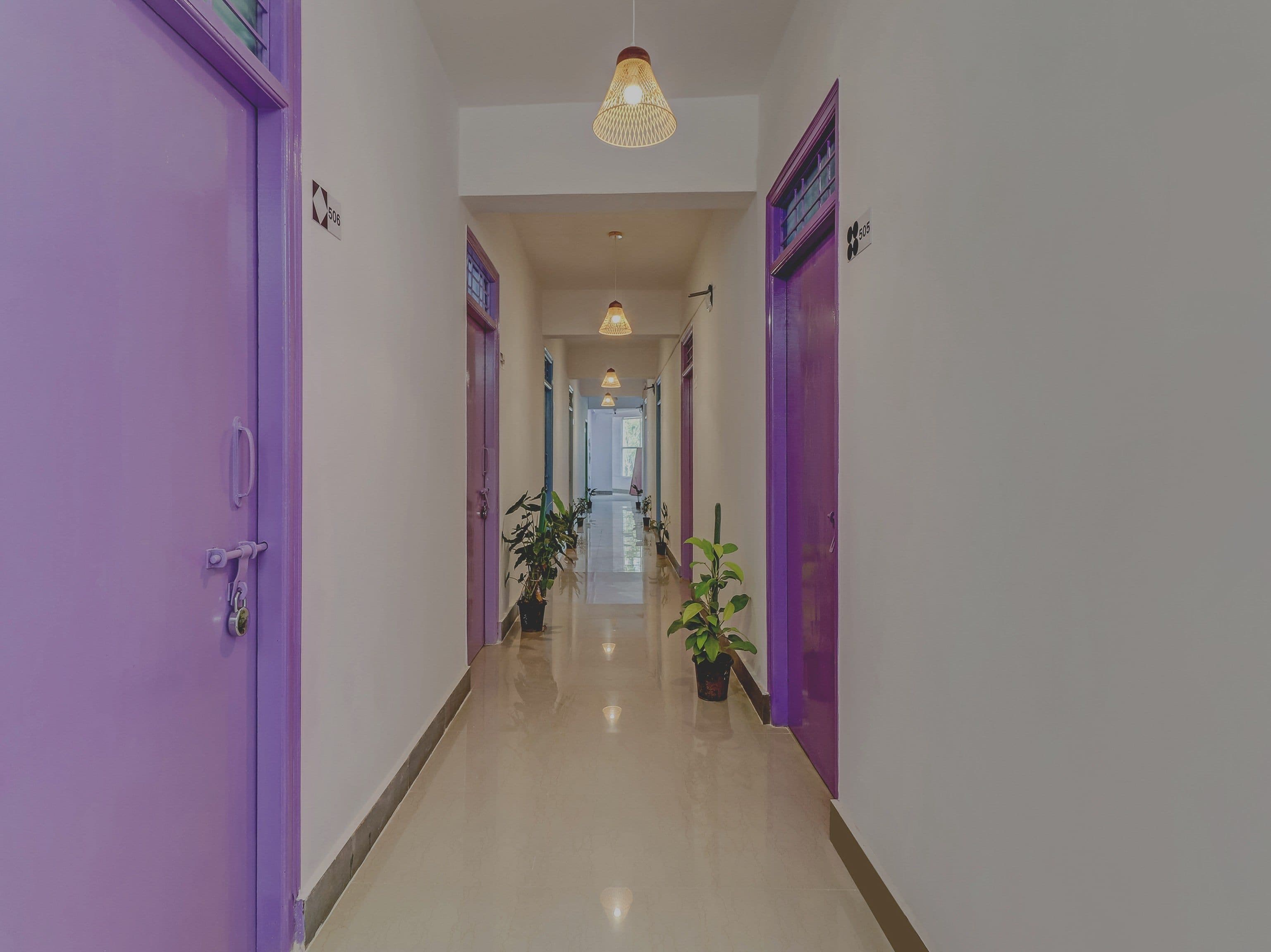 A hallway with purple doors, potted plants, and hanging lights.