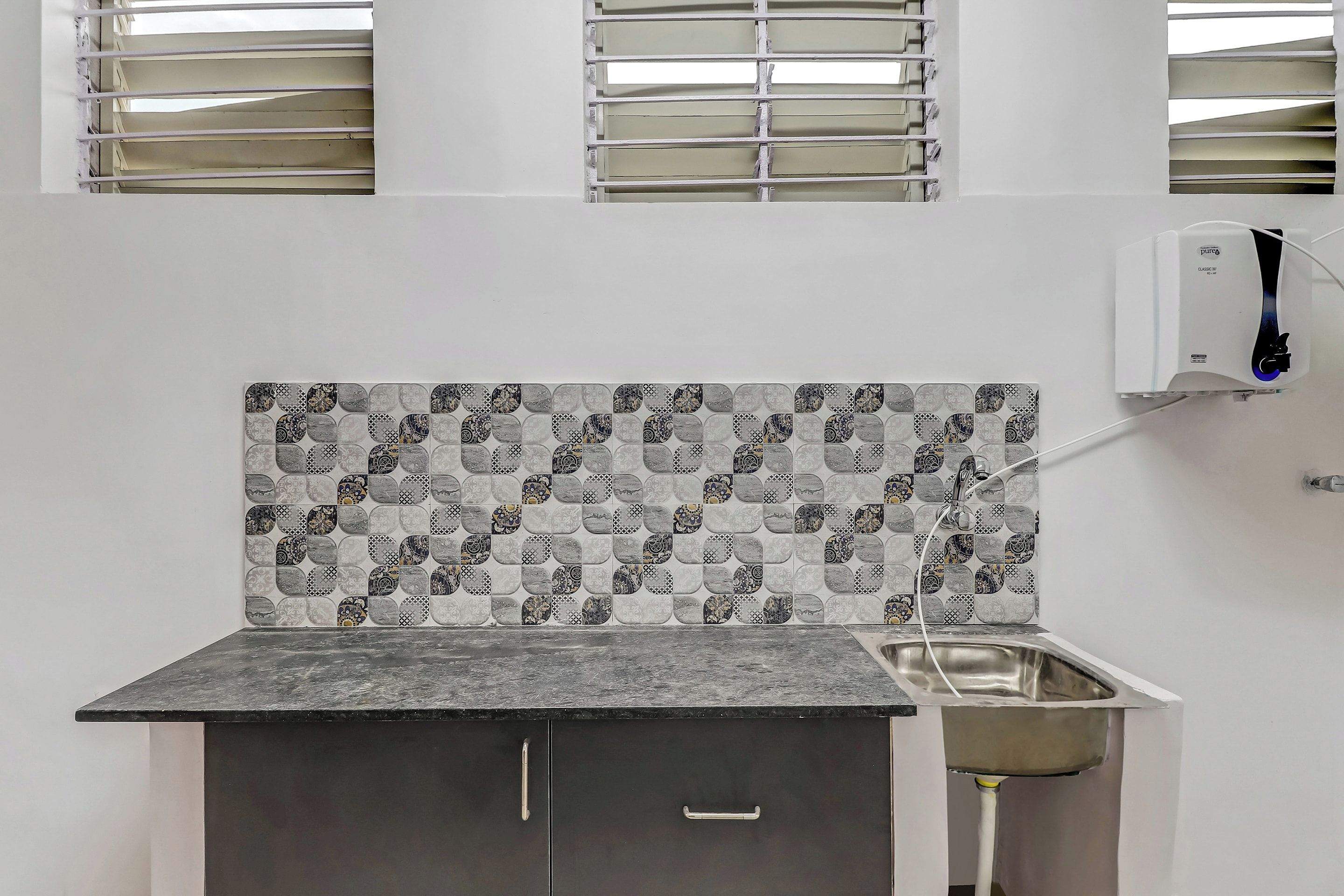 A kitchen with a patterned backsplash, a built-in sink, and a cabinet.
