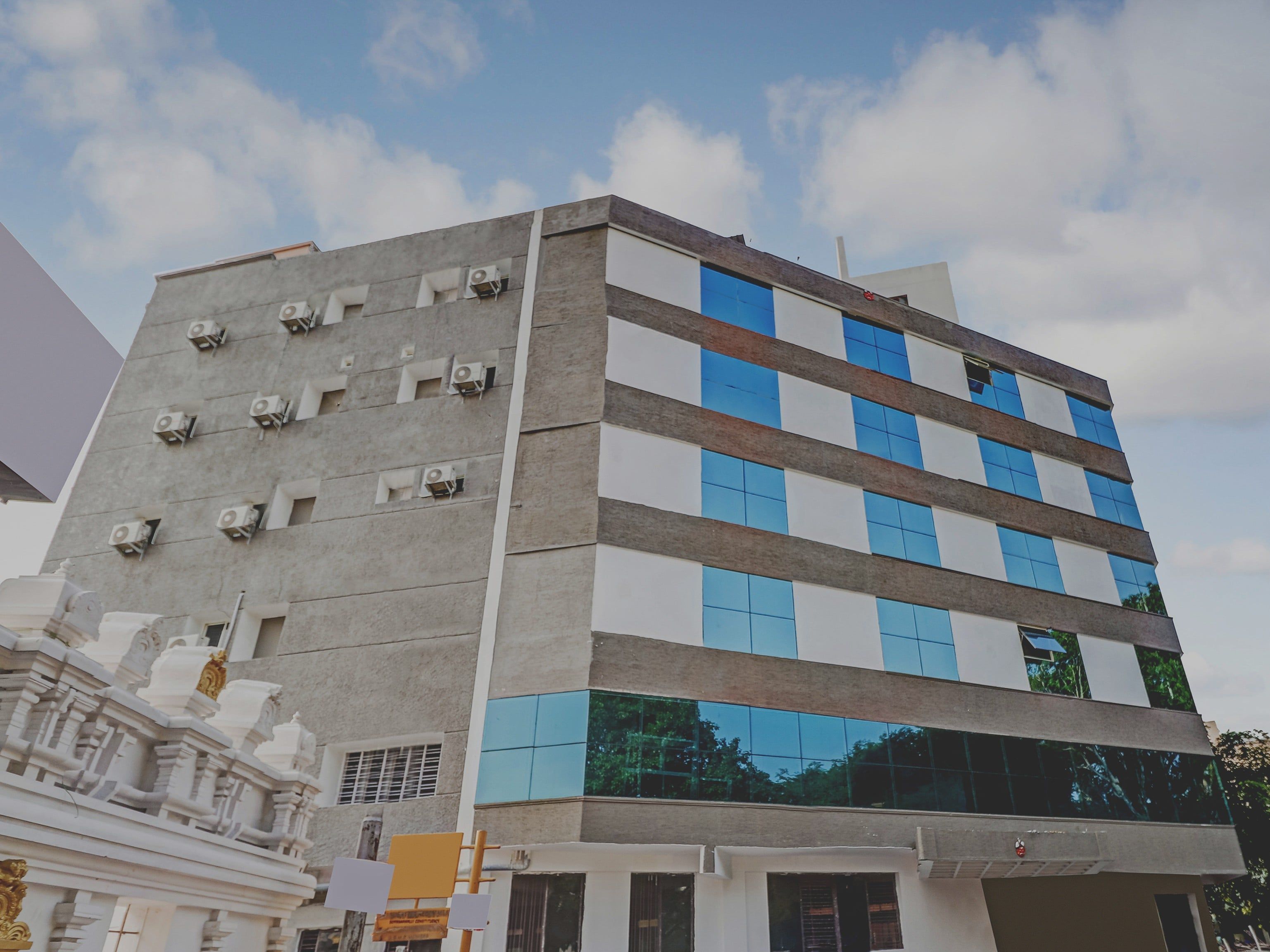 Un edificio de varios pisos con un diseño arquitectónico moderno, que combina fachadas de vidrio y hormigón.