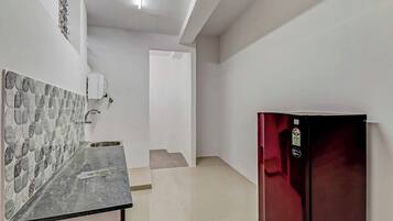 Una cocina con salpicadero de azulejos, un lavamanos de acero inoxidable y un refrigerador rojo.