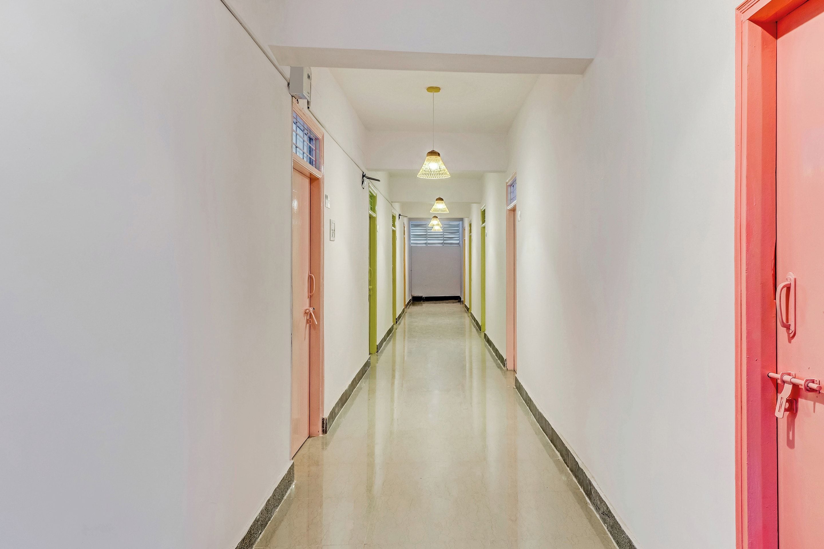 A corridor with doors on both sides, a ceiling light fixture, and a tiled floor.