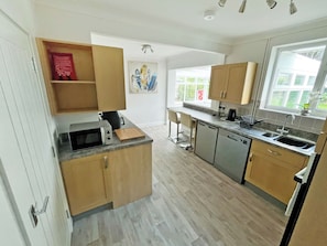 A modern kitchen with wooden cabinets, a microwave, a coffee maker, and a sink. - 2 bedroom accommodation in Bodham, near Sheringham (Bodham, near Sheringham)