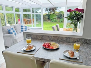 A breakfast setup with croissants, fruit, and orange juice on a kitchen counter with a view of a garden. - 2 bedroom accommodation in Bodham, near Sheringham (Bodham, near Sheringham)