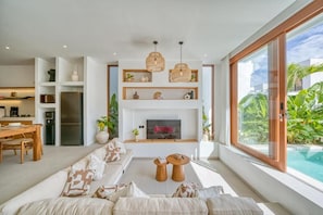 Una sala moderna con un sofá grande, una chimenea y vistas a una piscina.