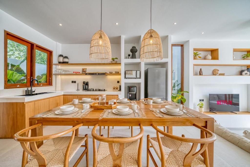 A modern kitchen with a dining area, wooden furniture, and pendant lighting.