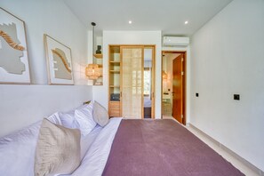 Ein Schlafzimmer mit einem Bett, einem Kleiderschrank, einem Nachttisch und einer Wand-Klimaanlage.