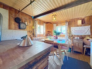 A wooden interior with a kitchen area, a dining table, and a seating arrangement. - Schneehitzalmhütte by Interhome (Wörschach)