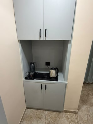 Una kitchenette con una encimera, un hervidor y una cafetera.