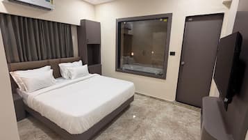 Een hotelkamer met een bed, een televisie, een raam, een douche en een plafondventilator.