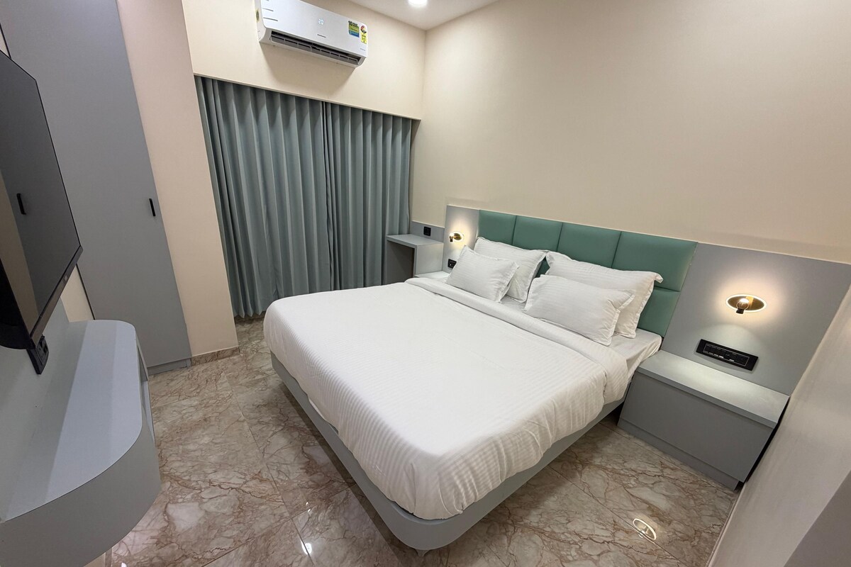 Una habitación de hotel con una cama, una mesita de noche, un aire acondicionado de pared y una cortina.