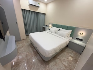 Una habitación de hotel con una cama, una mesita de noche, un aire acondicionado de pared y una cortina.