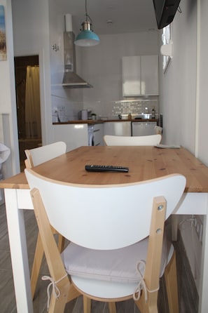 A dining area with a wooden table, white chairs, and a remote control on the table. - Apartment 'Calma' with Wi-Fi (Tarifa)