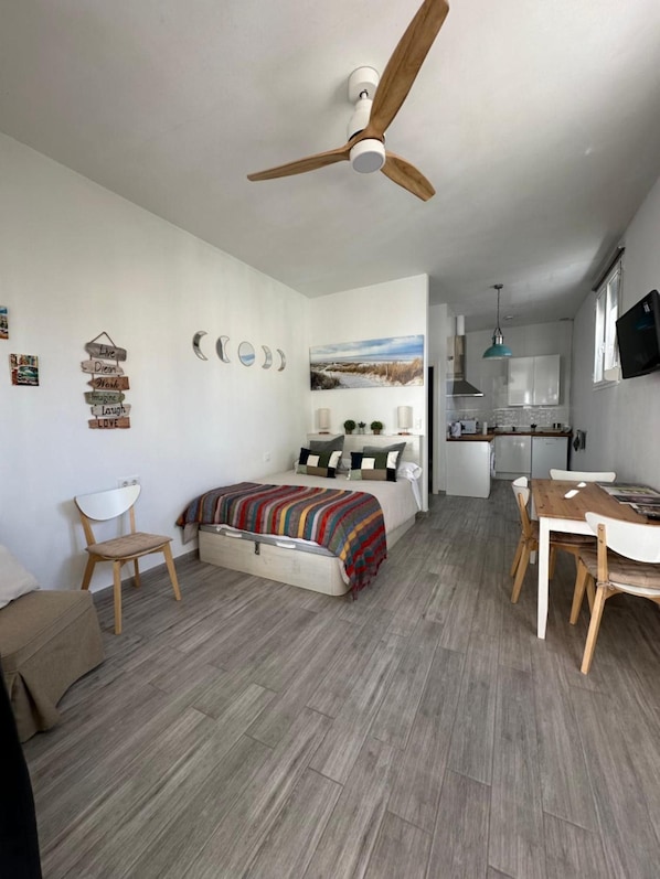 A compact bedroom with a bed, a desk, and a kitchenette. - Apartment 'Calma' with Wi-Fi (Tarifa)