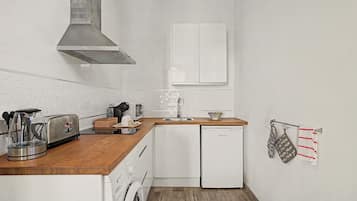 Una cocina compacta con tostadora, hervidor, microondas, lavaplatos y lavamanos.