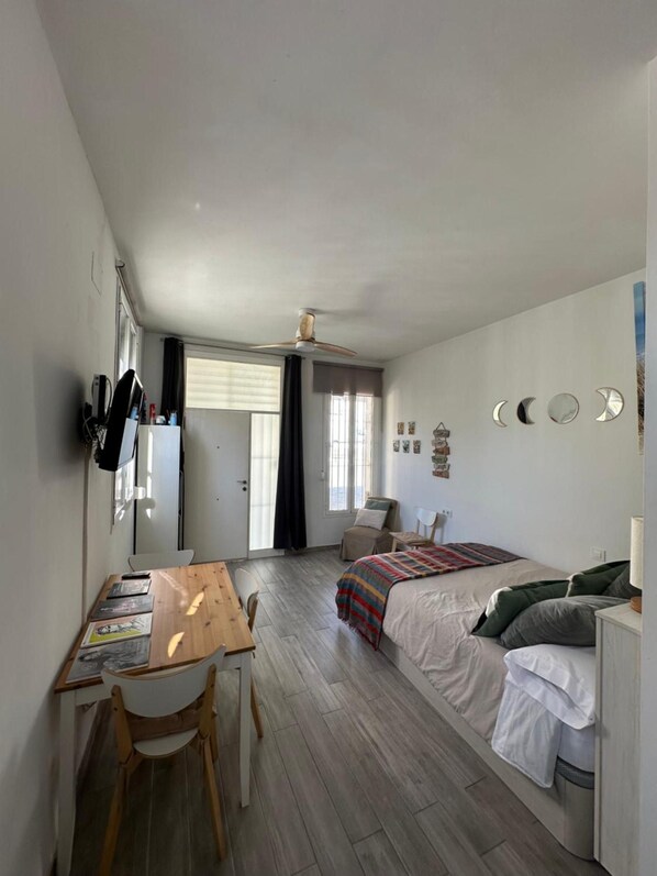 A room with a bed, a desk, a chair, a ceiling fan, and a window. - Apartment 'Calma' with Wi-Fi (Tarifa)